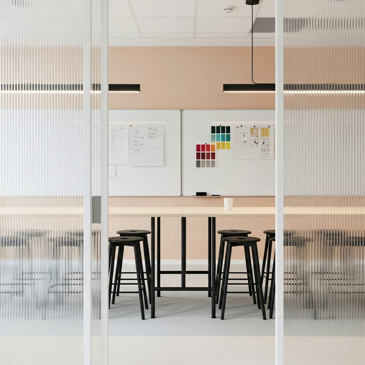The Amarante studio floor seen through its ribbed glass partition, one long worktable set for a review